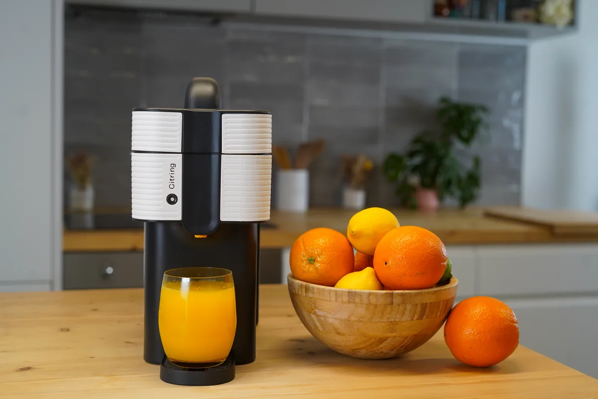 Citring One Orangenpresse auf einer hellen Küchenzeile neben einer Schale Orangen